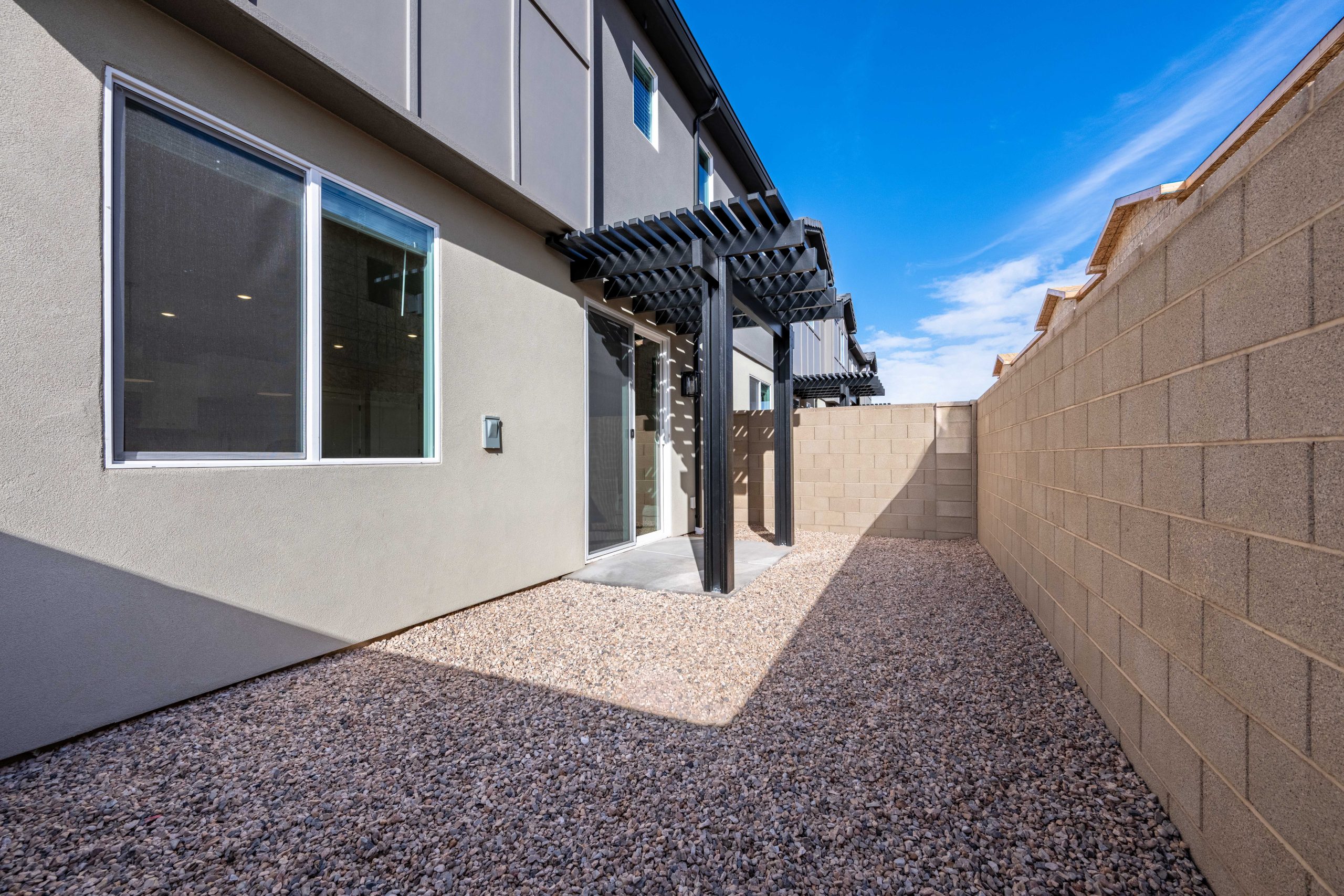 Private backyard patio with modern pergola and low-maintenance desert landscaping at the Sunrise townhome in Rise, Washington, Utah.