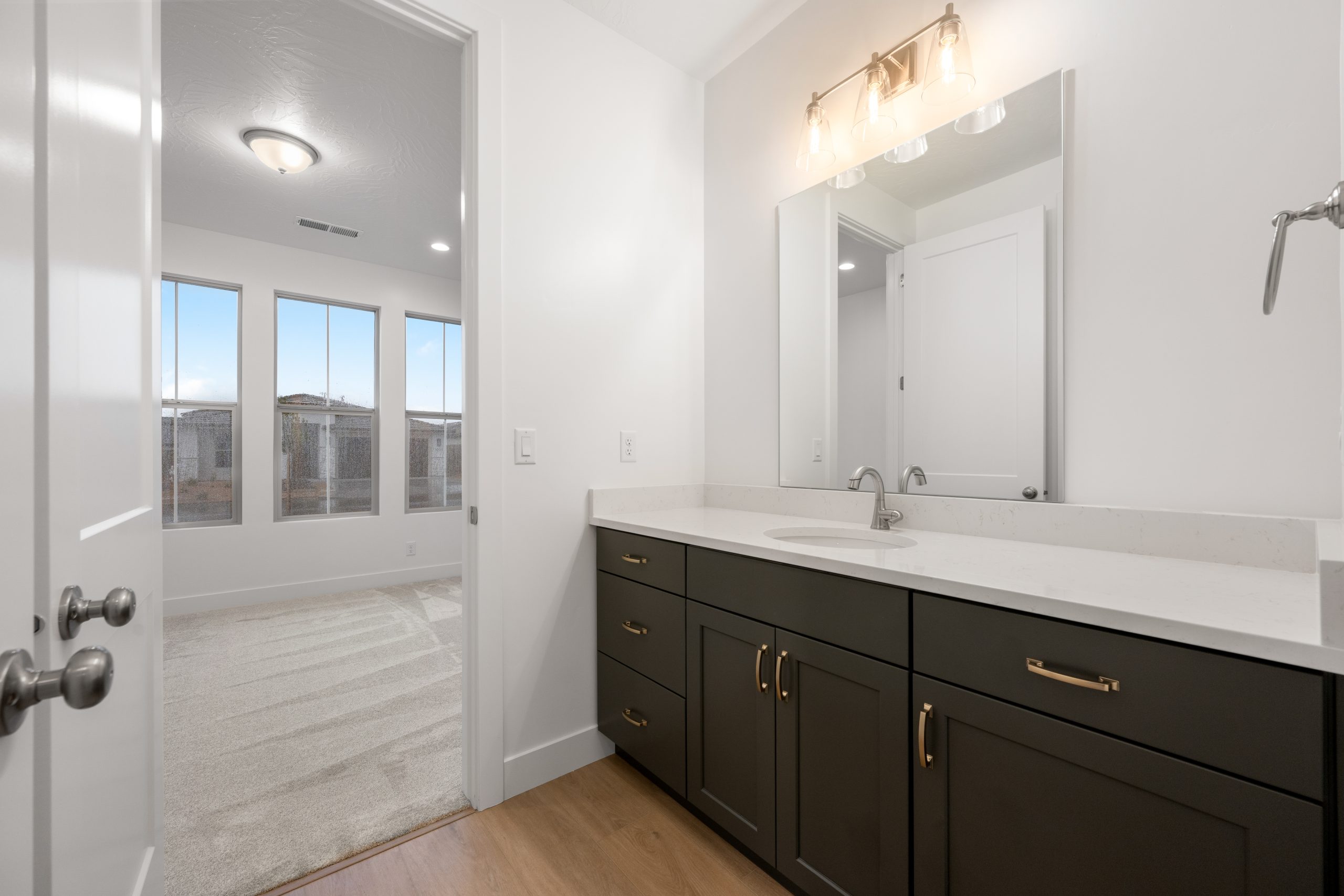 Modern bathroom in the Mesa floor plan at Solis by Cole West in Washington, Utah, featuring dark cabinetry, white countertops, and brushed nickel fixtures.