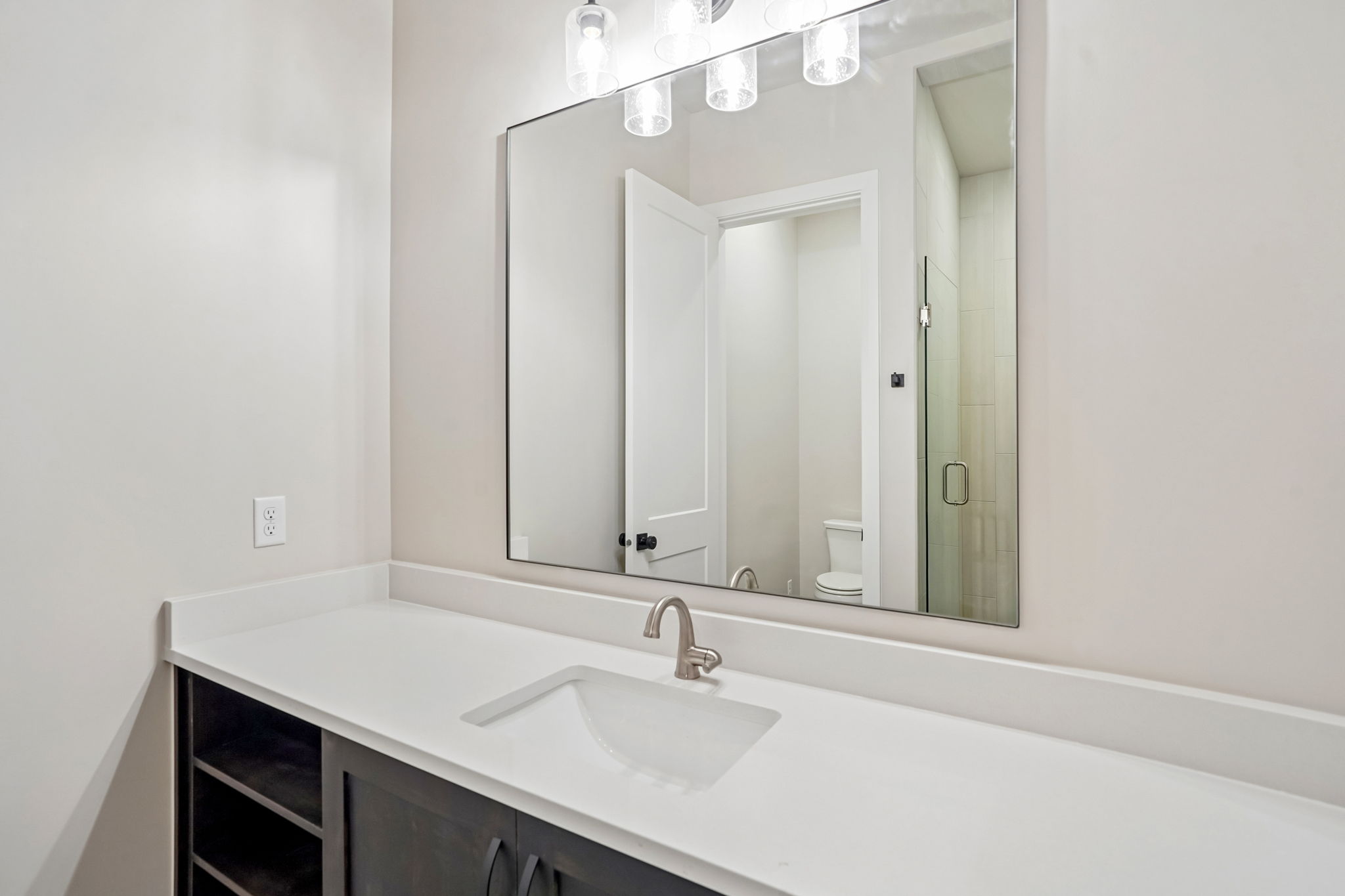 Modern bathroom in the Pacific II at Desert Color featuring a white countertop, dark cabinetry, brushed nickel fixtures, and a large vanity mirror.