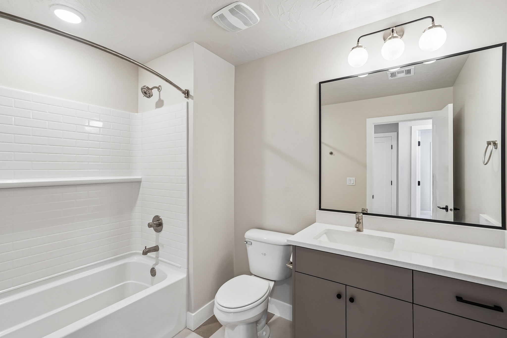Bright bathroom featuring a tub-shower combination, white subway tile, and contemporary vanity.
