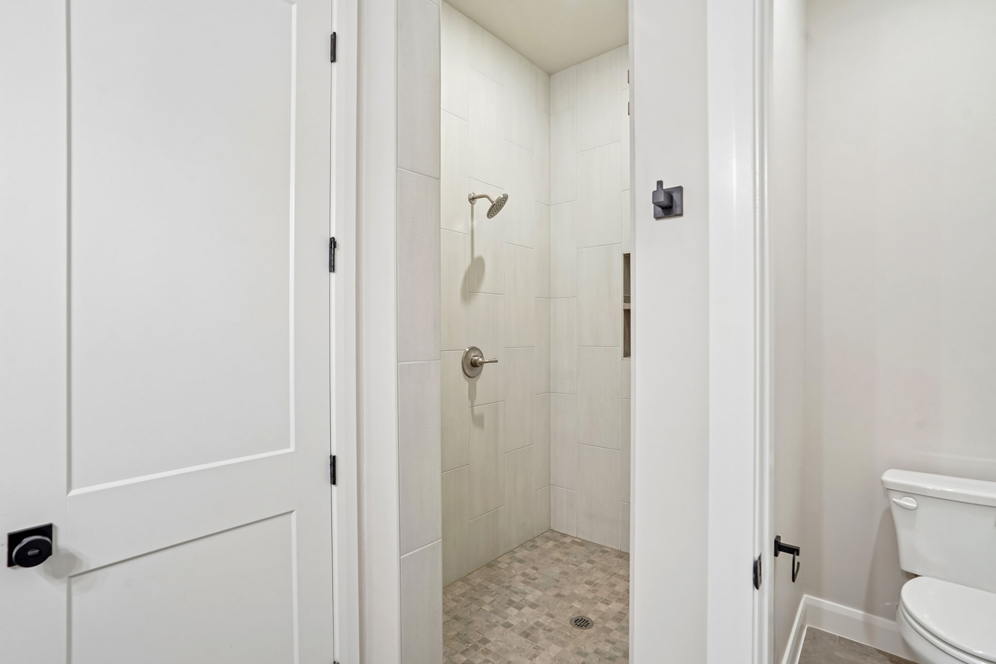 Walk-in shower in the Pacific II at Desert Color in St. George, Utah, featuring neutral tile walls, mosaic tile flooring, and brushed nickel fixtures.