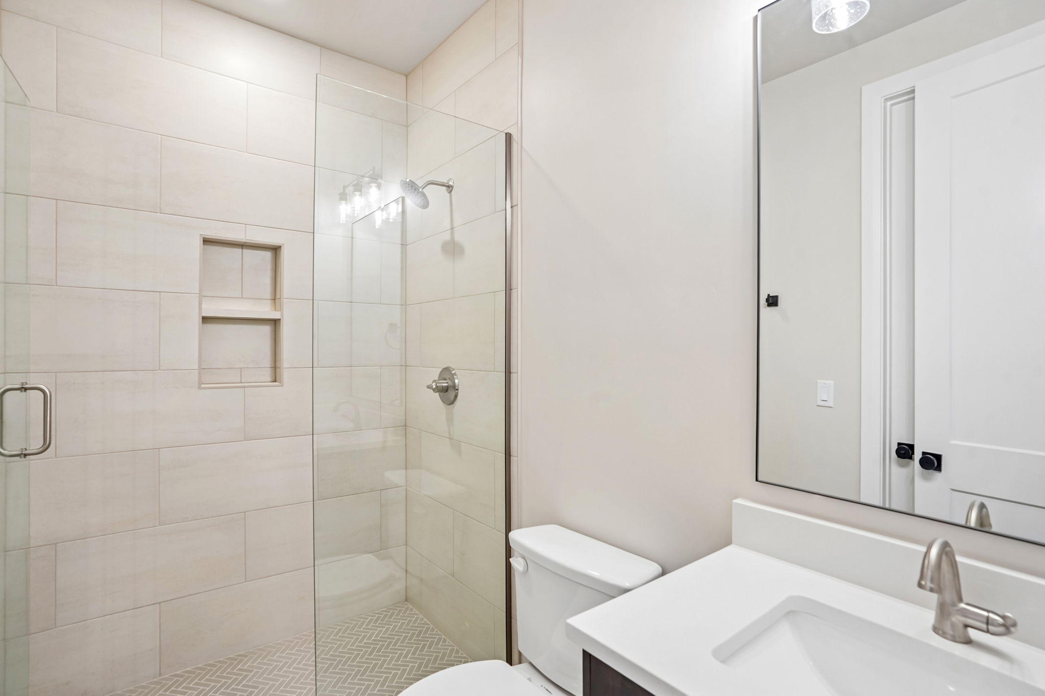 Contemporary bathroom in the Pacific II by Cole West featuring a glass-enclosed walk-in shower, built-in shower niche, and modern white vanity.
