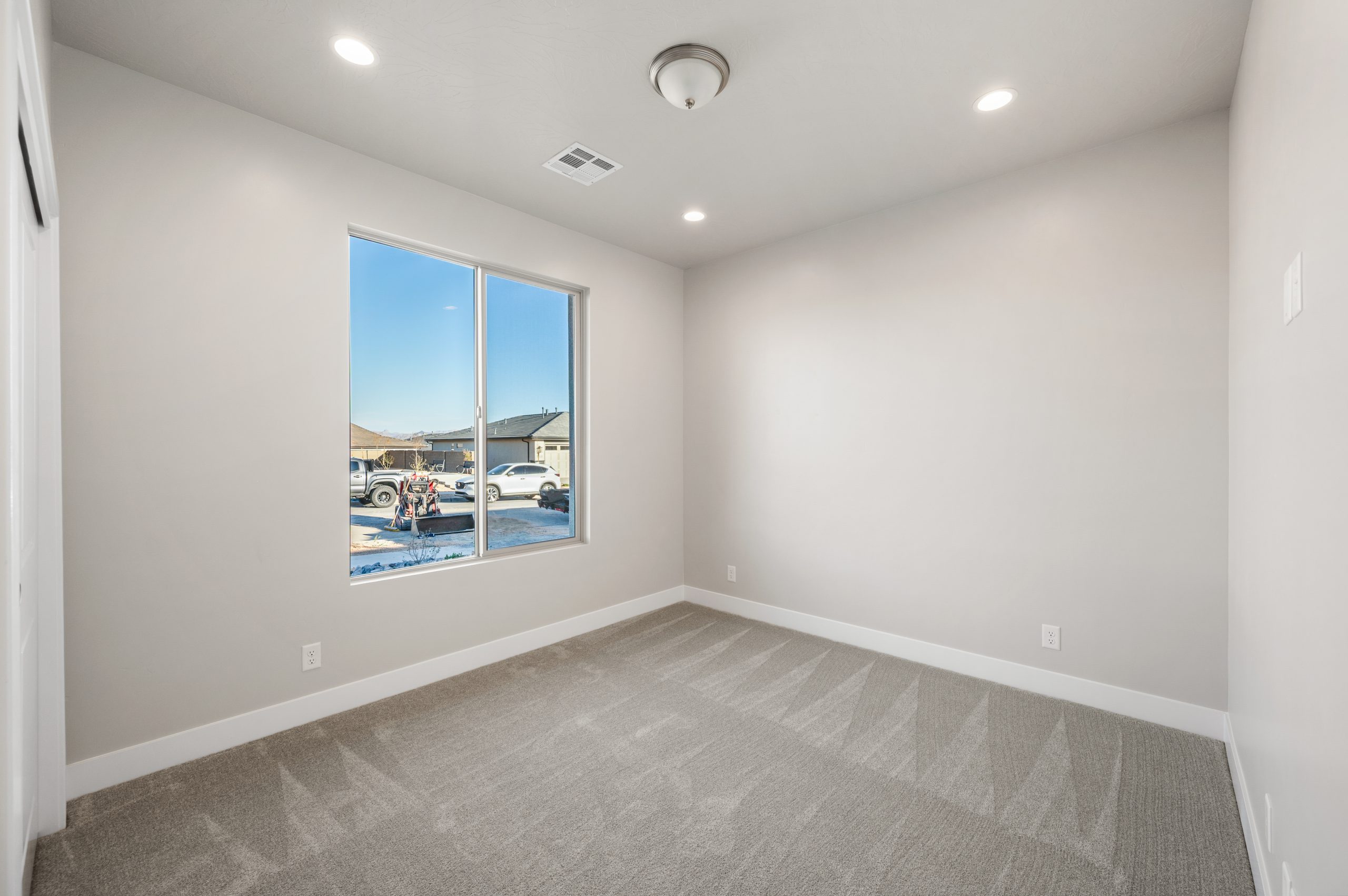 Bright secondary bedroom featuring soft neutral carpeting, modern finishes, and a large window in the Mojave floor plan at Solis by Cole West.