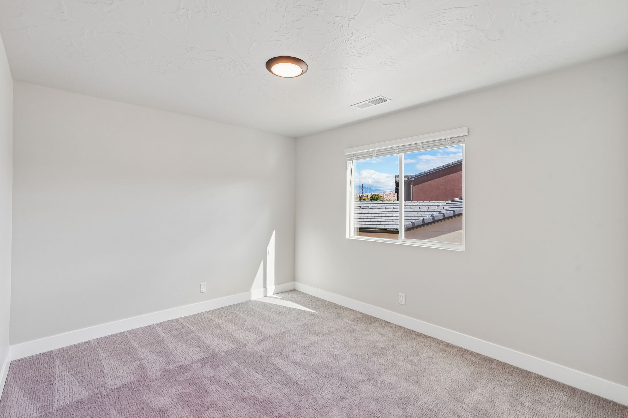 Spacious bedroom with soft carpeting, neutral finishes, and natural light.