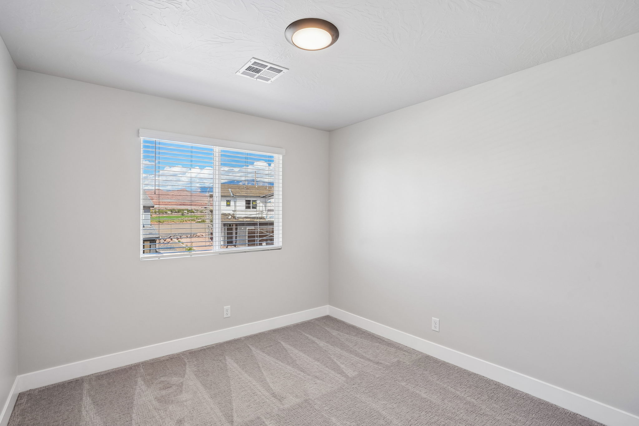 Naturally lit bedroom in the Sunburst townhome by Cole West, featuring modern finishes, neutral carpeting, and mountain views from the window.