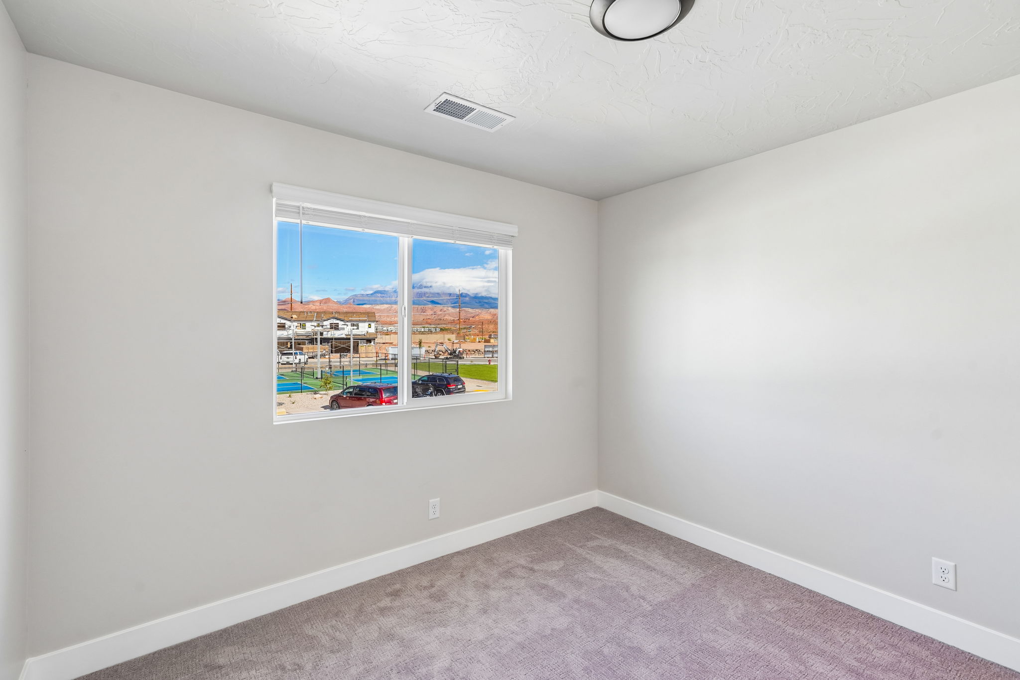 Bright bedroom offering scenic Southern Utah mountain views and soft carpeting.