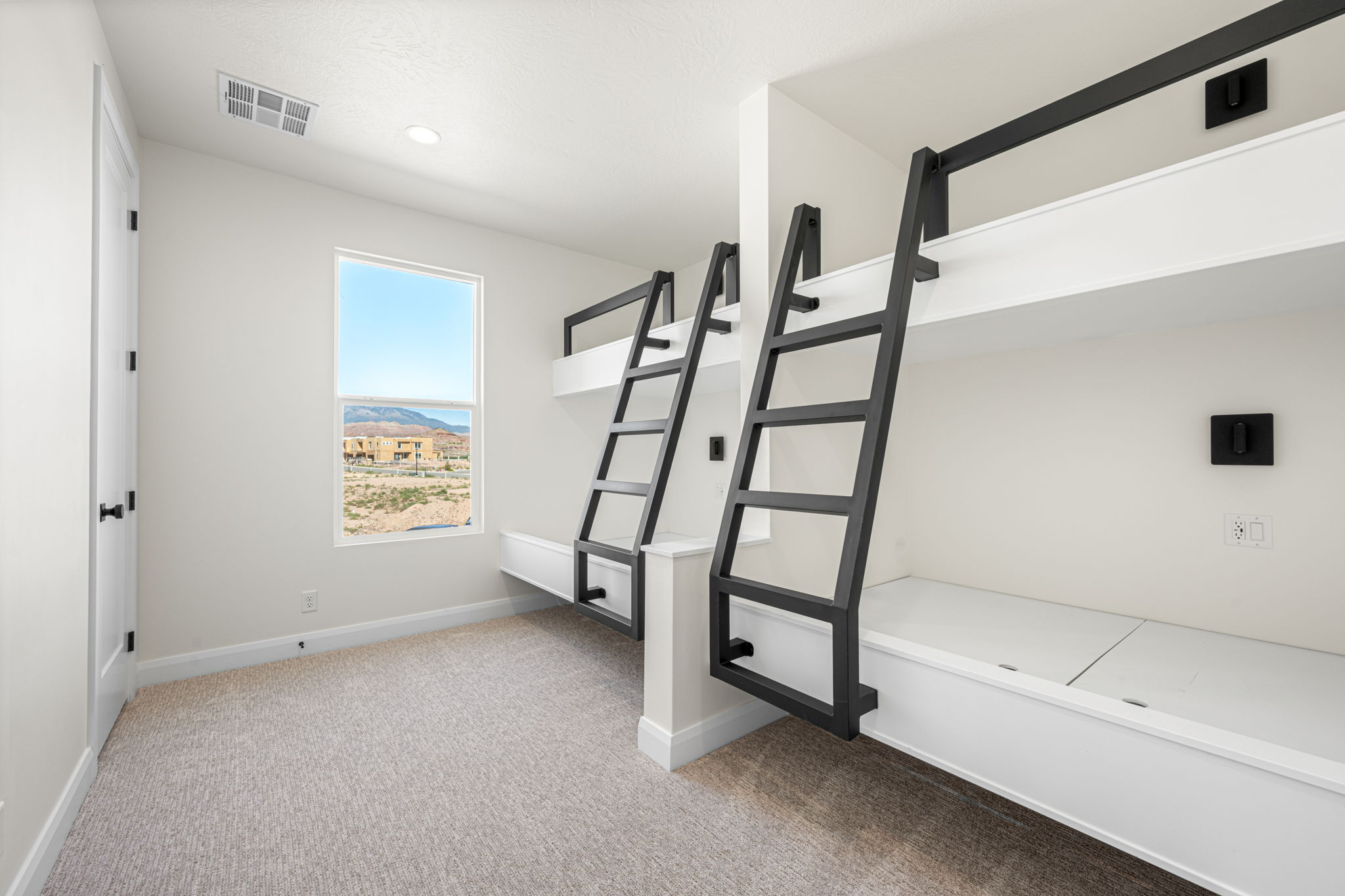 Custom built-in bunk room featuring two sets of white bunk beds, black metal ladders, and a large window with mountain views.