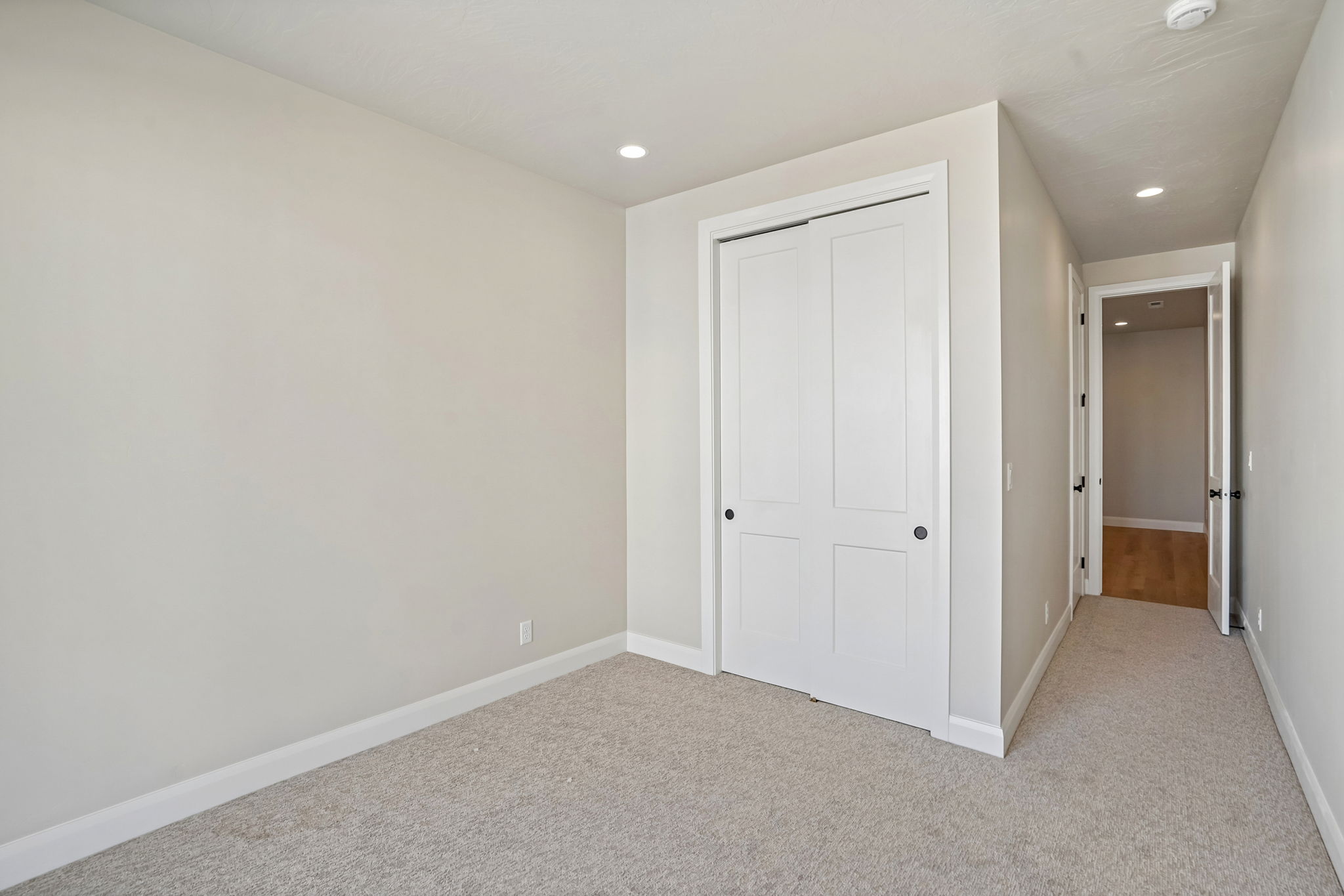 Modern bedroom in the Pacific II at Desert Color featuring a spacious closet, neutral carpeting, recessed lighting, and contemporary white trim.