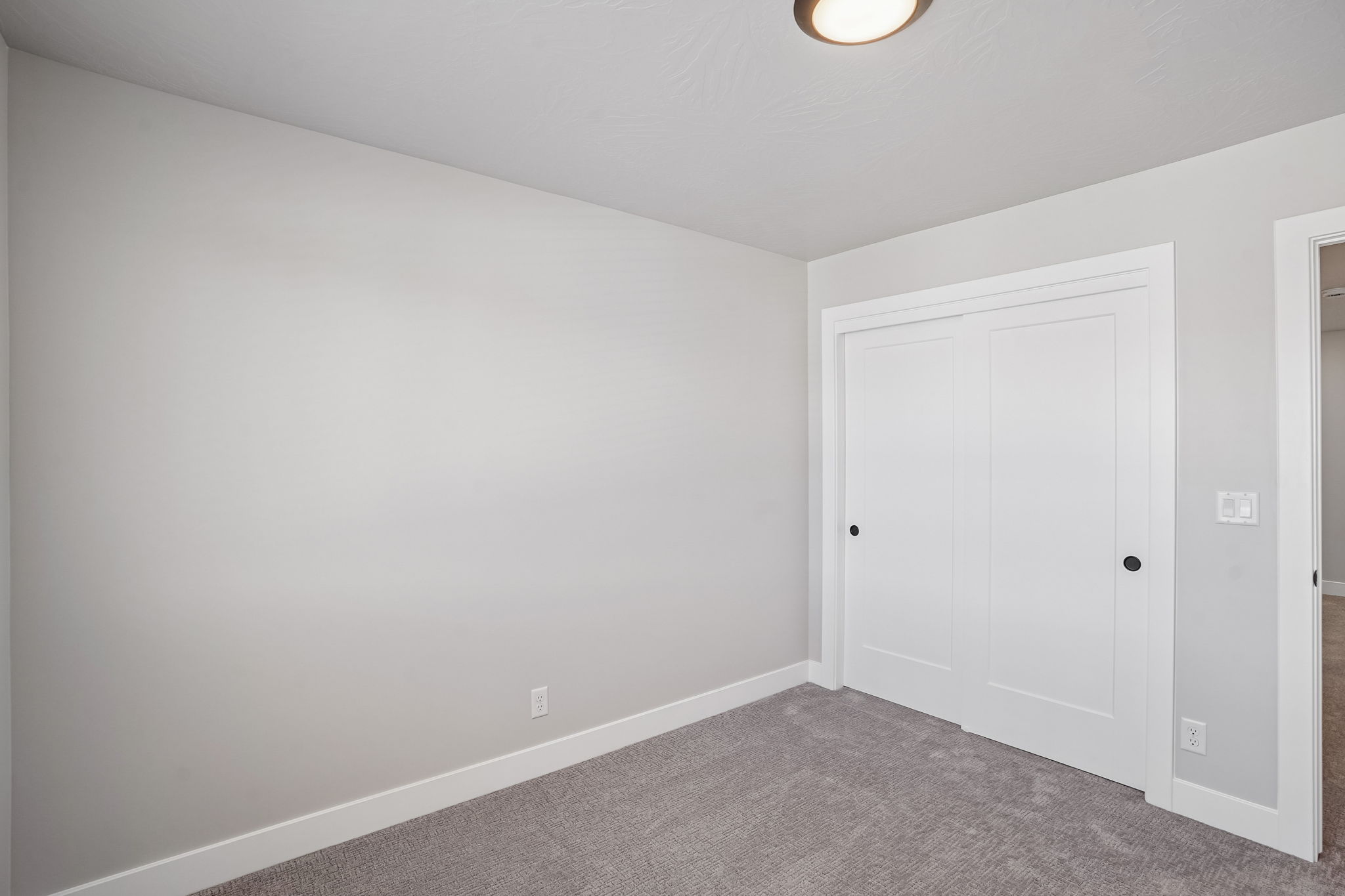 Additional view of a bedroom in the Sunburst floor plan at Rise, showcasing neutral finishes, soft carpeting, and a spacious closet.