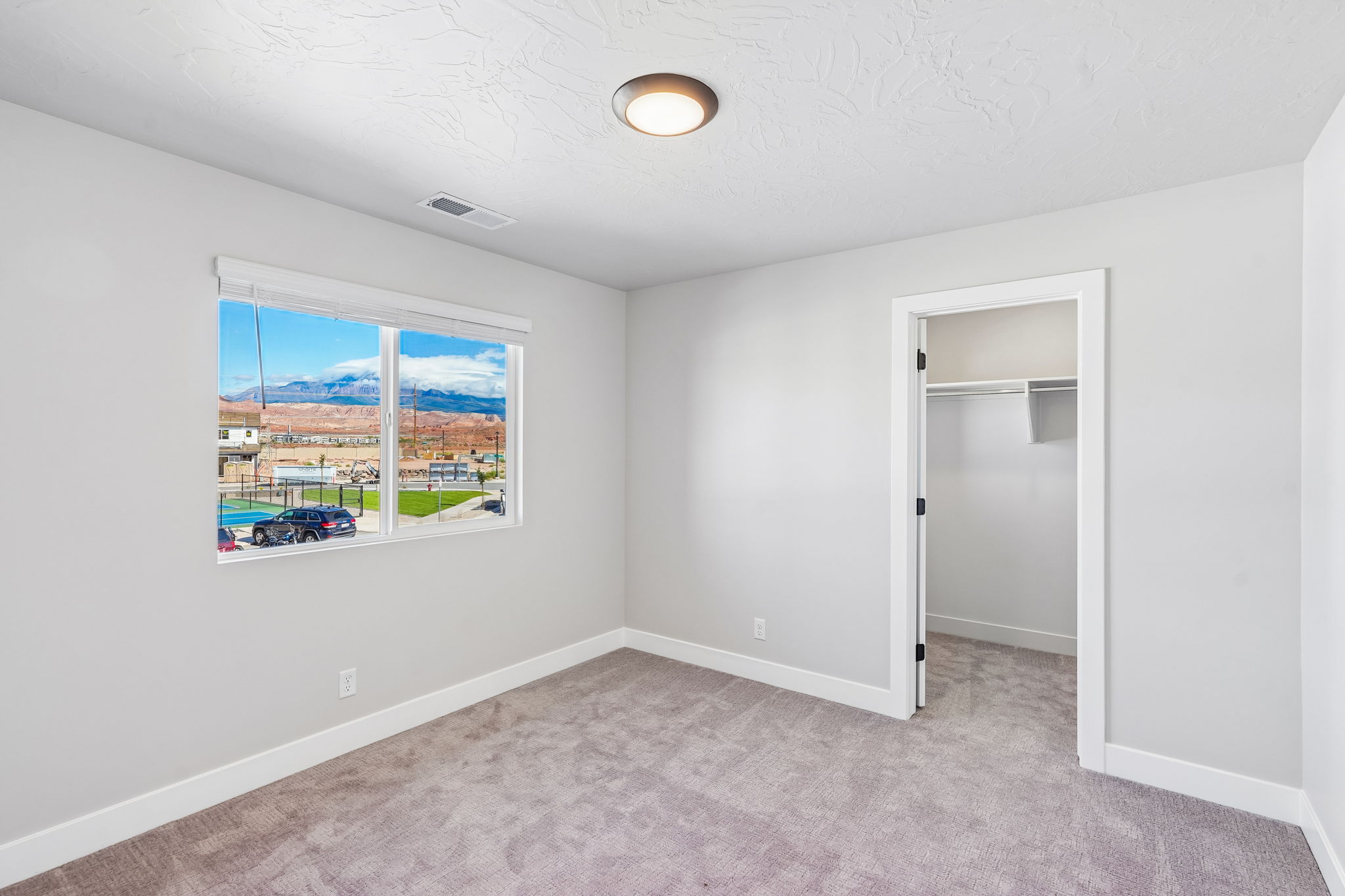 Inviting bedroom featuring natural light, neutral finishes, and a spacious walk-in closet.