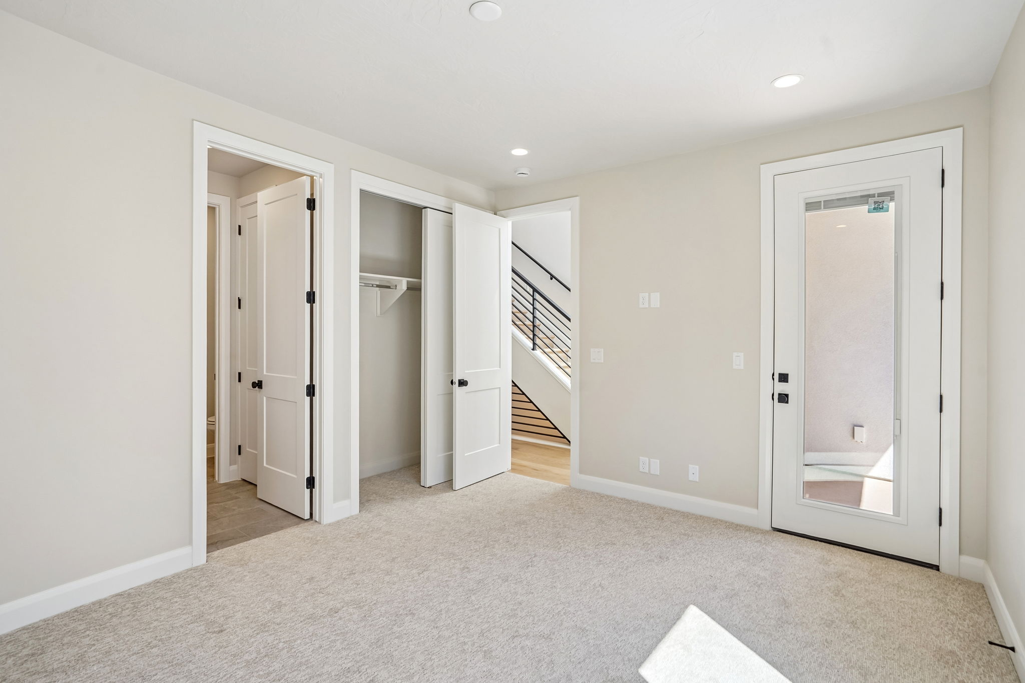 Versatile bedroom in the Pacific II at Desert Color featuring plush carpeting, a built-in closet, and direct access to an outdoor patio.