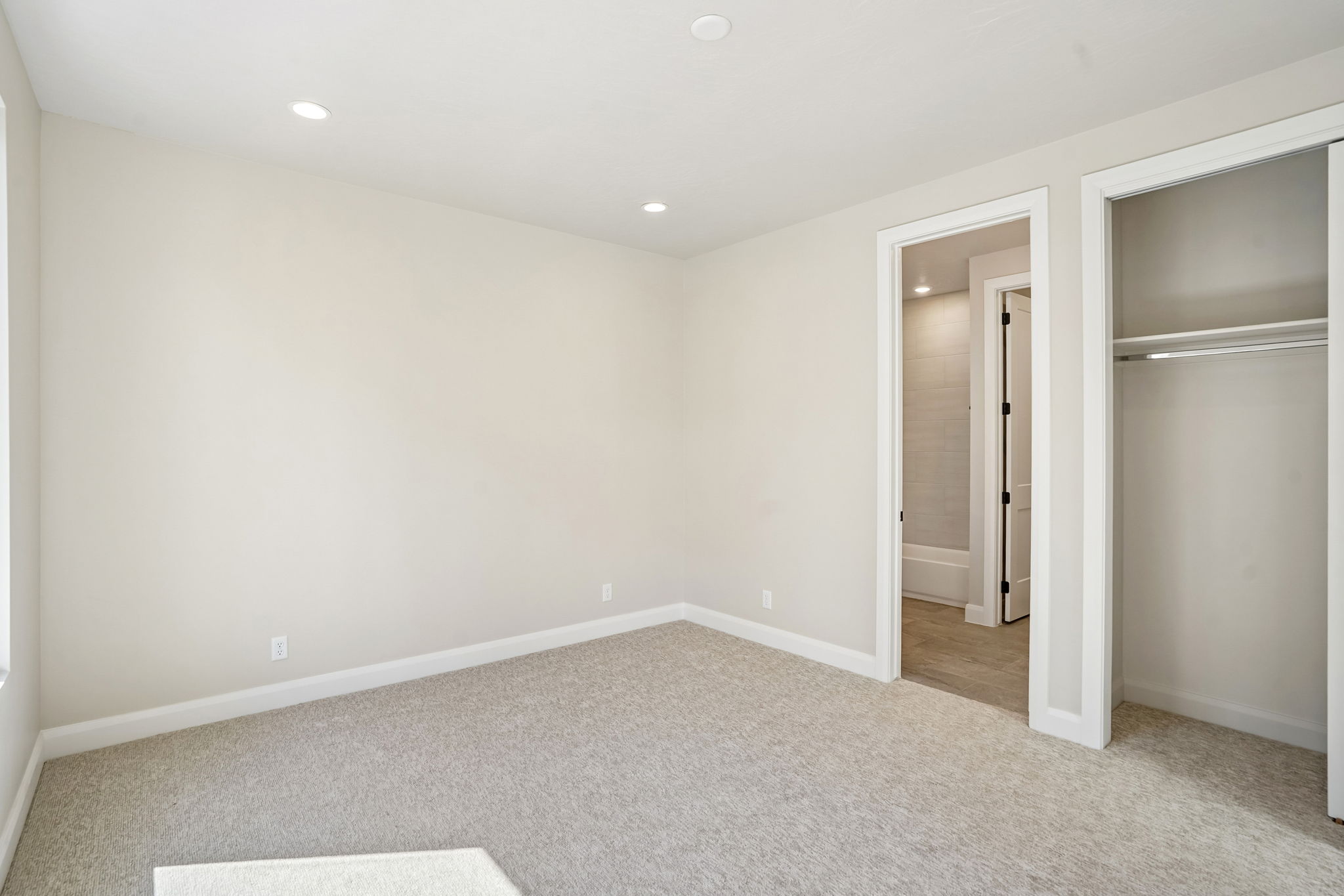 Bright bedroom in the Pacific II at Desert Color featuring neutral walls, recessed ceiling lights, and an open closet near the adjoining bathroom.