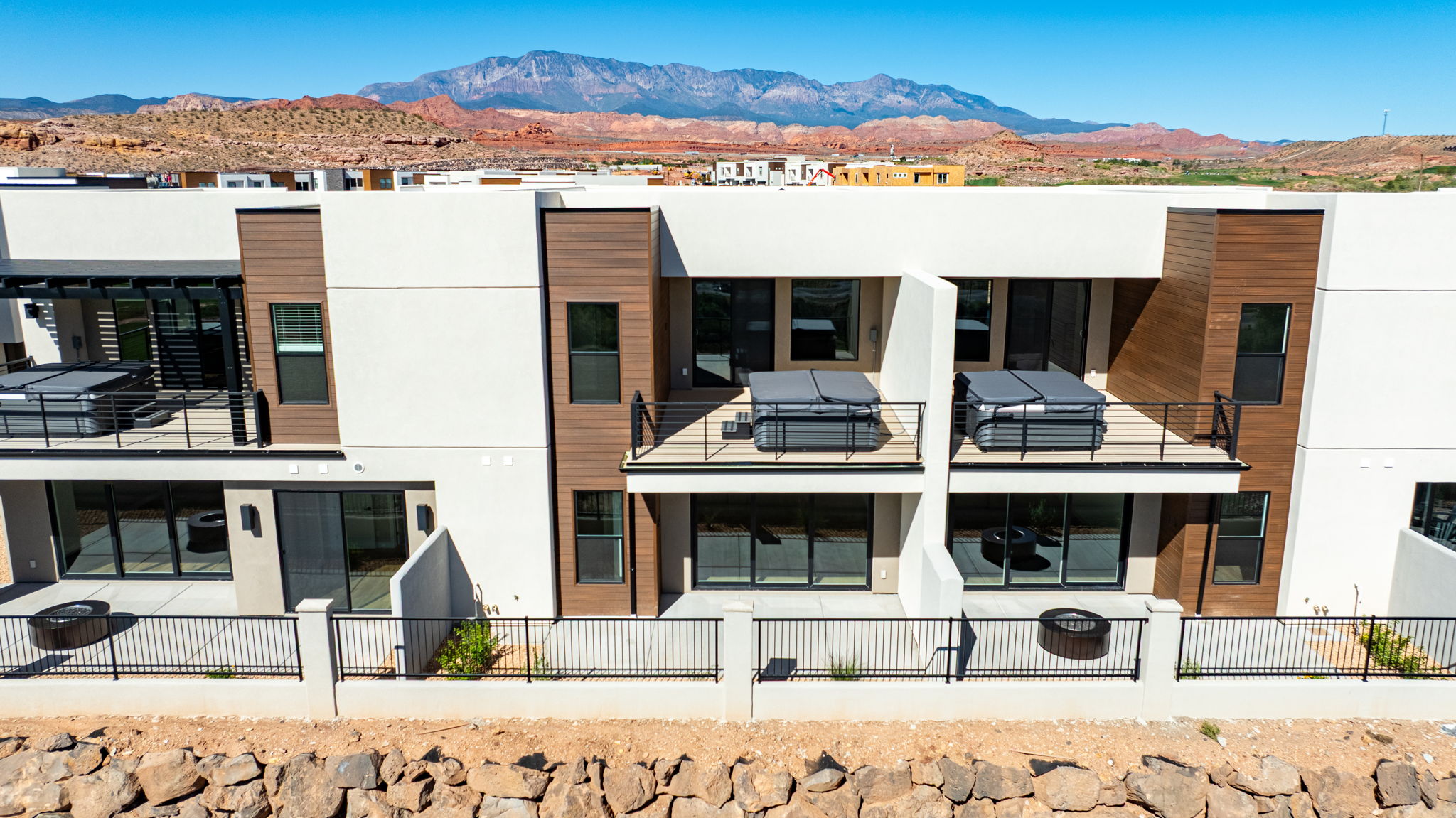 Rear exterior of modern Bahama townhomes at Isle by Cole West, featuring private balconies with hot tubs, contemporary finishes, and mountain views.