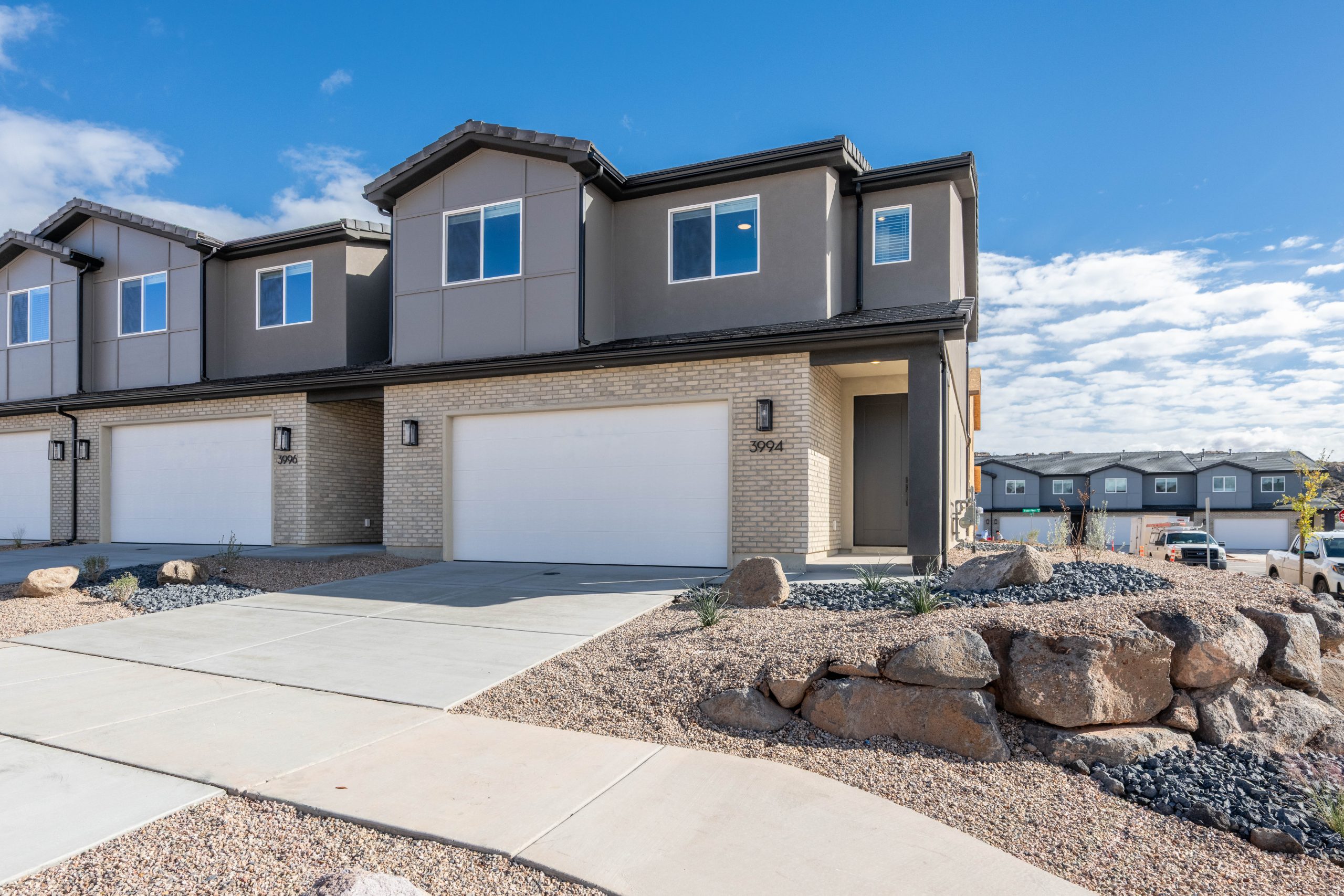 Modern two-story Sunrise end-unit townhome at Rise by Cole West in Washington, Utah, featuring contemporary architecture, stone accents, and an attached garage.
