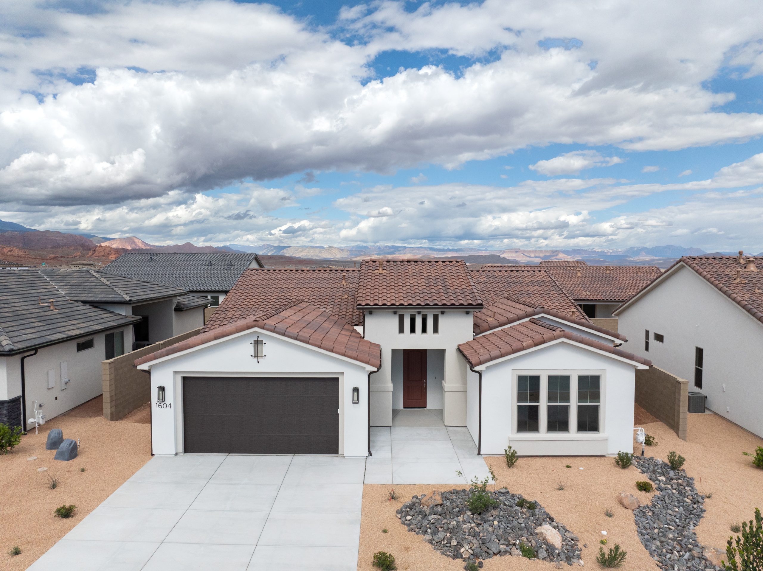 Front exterior of the Mesa home at Solis by Cole West in Washington, Utah, featuring white stucco, a tile roof, two-car garage, and desert landscaping.