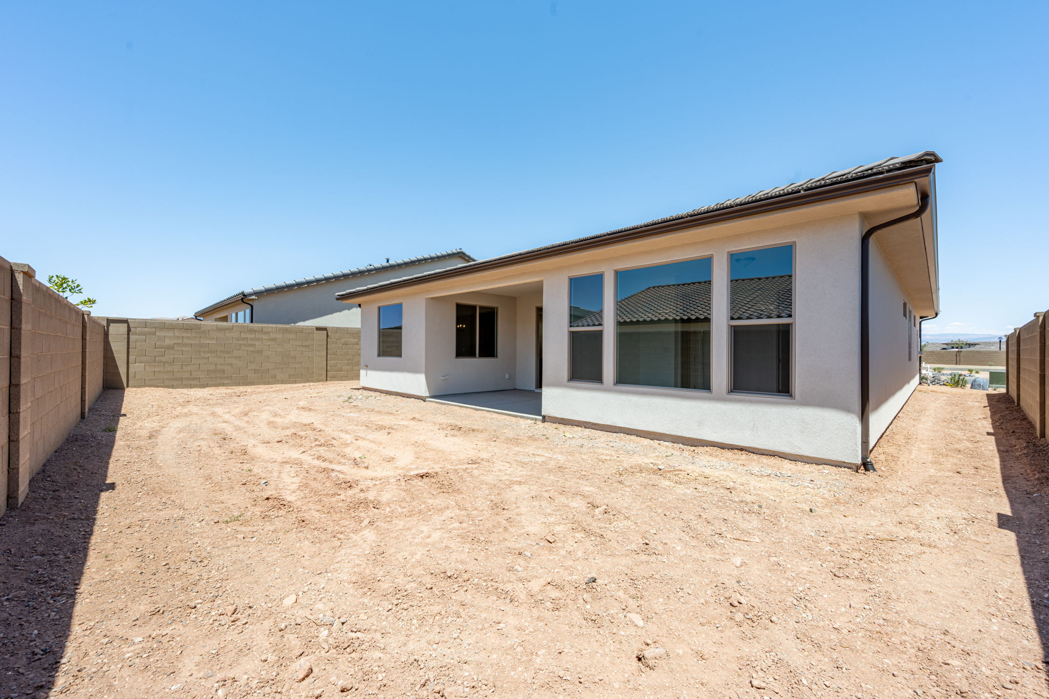Rear exterior of the Basin floor plan at Solis by Cole West, showcasing a covered patio, large windows, and a spacious backyard.