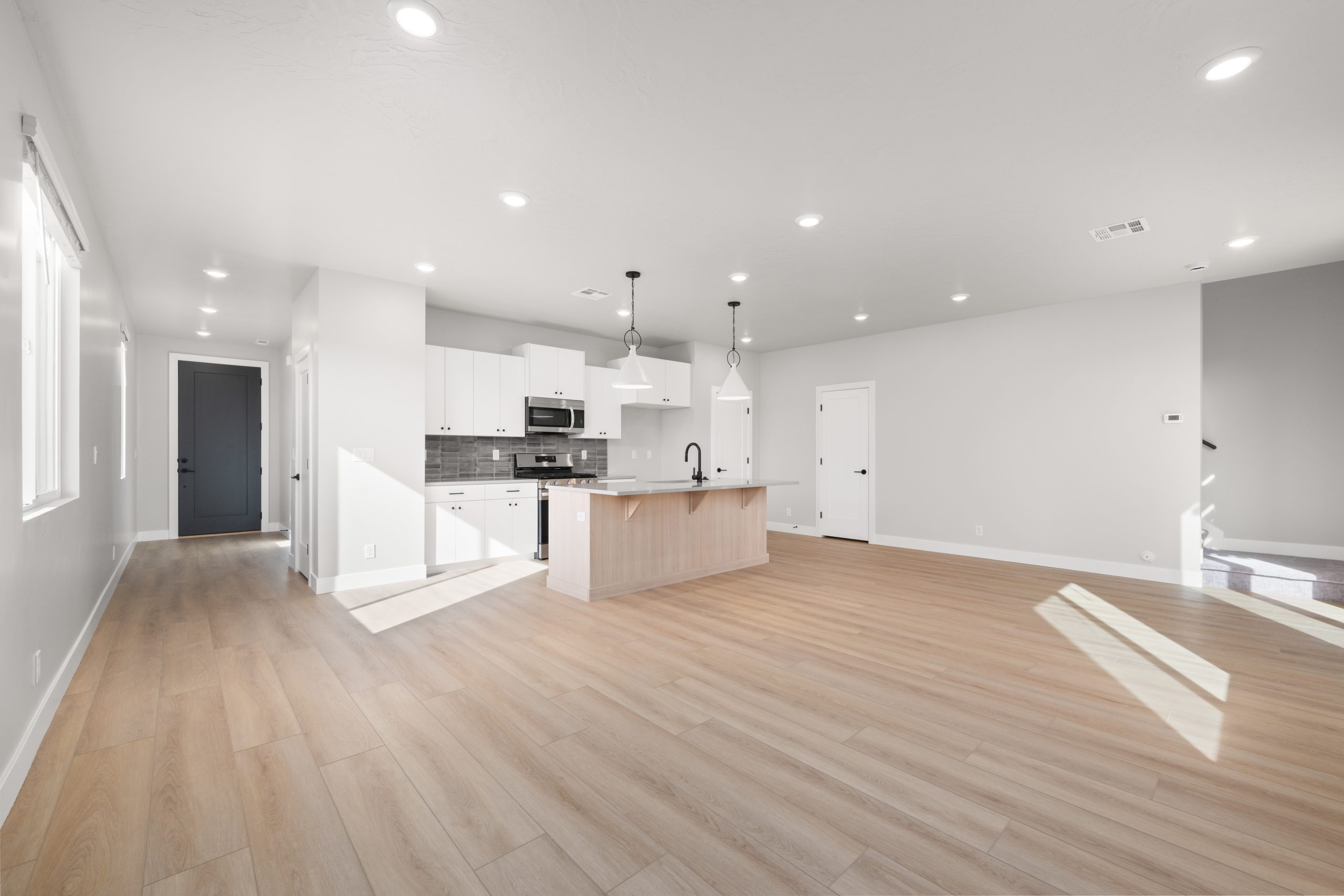 Spacious open-concept great room with luxury vinyl plank flooring, natural light, and a modern kitchen in the Sunrise floor plan at Rise by Cole West.