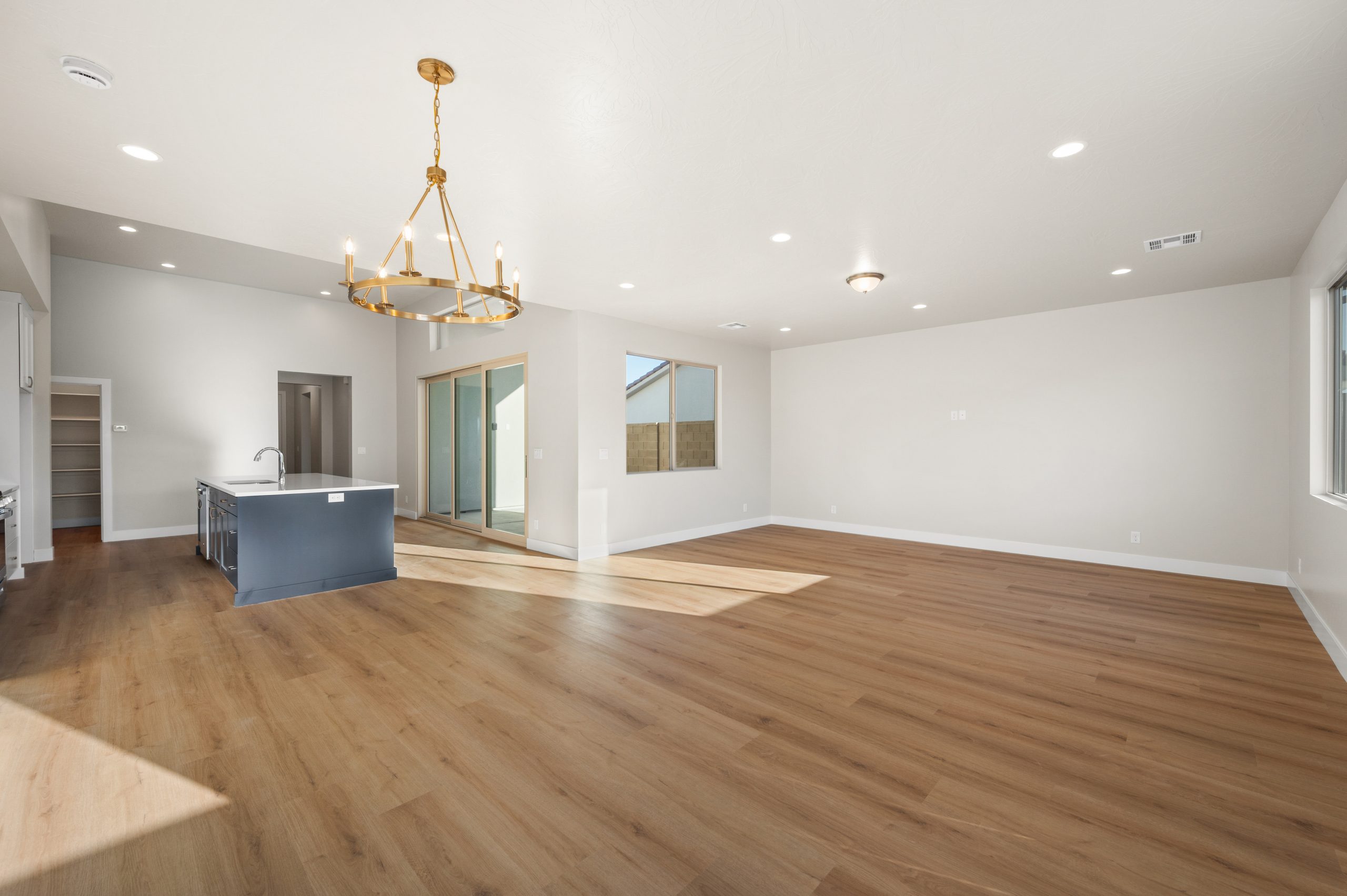 Bright living and dining area featuring an open floor plan, modern gold chandelier, and natural light in the Mojave home at Solis in Washington, Utah.