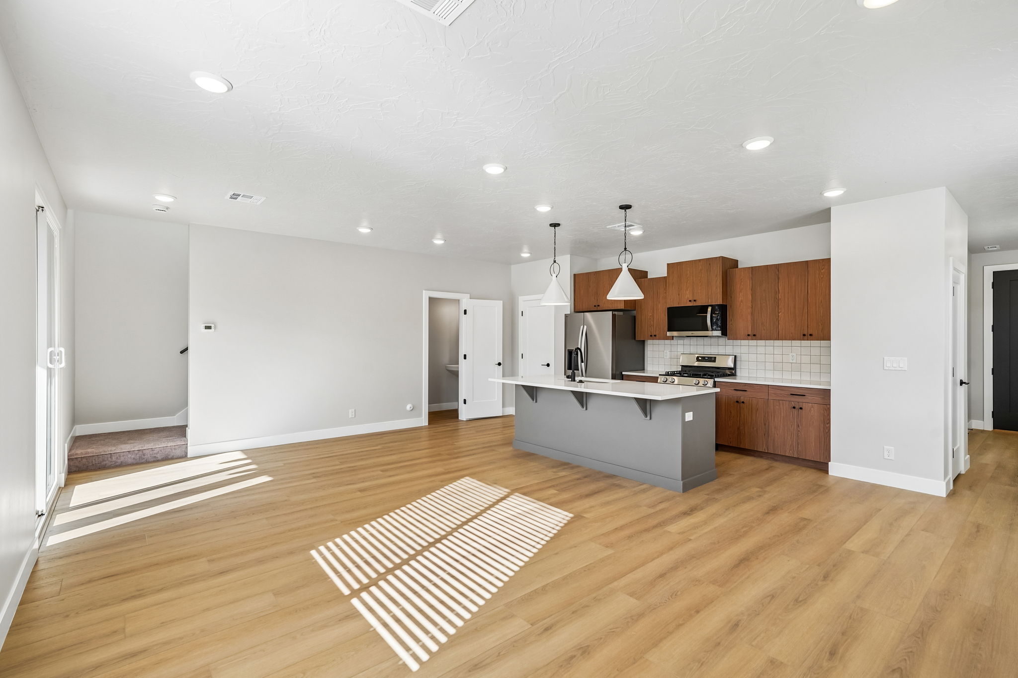 Expansive living space showcasing warm wood cabinetry, modern finishes, and an open layout.