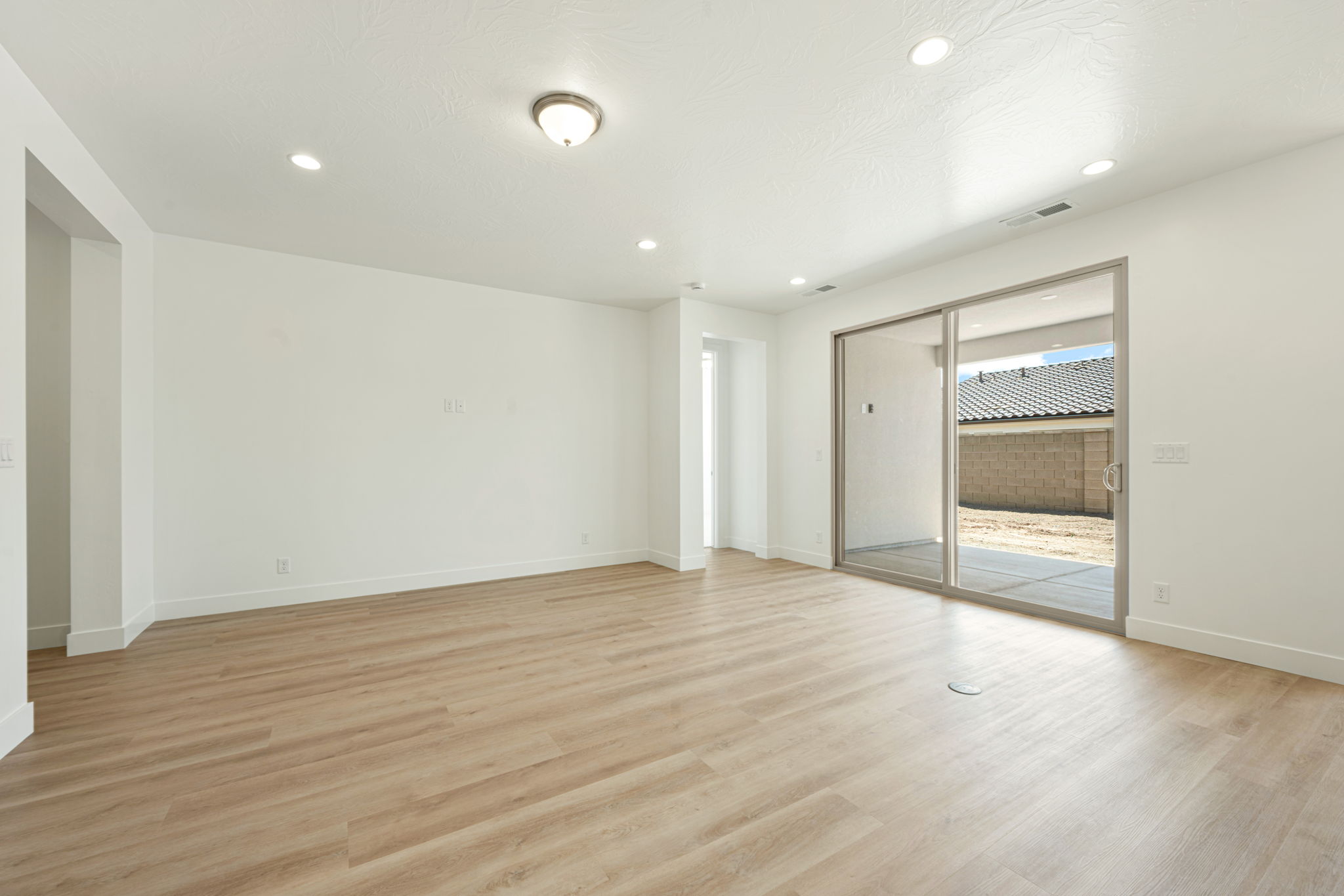 Spacious living room in the Basin floor plan at Solis in Washington, Utah, featuring modern flooring, bright white walls, and large sliding glass doors.