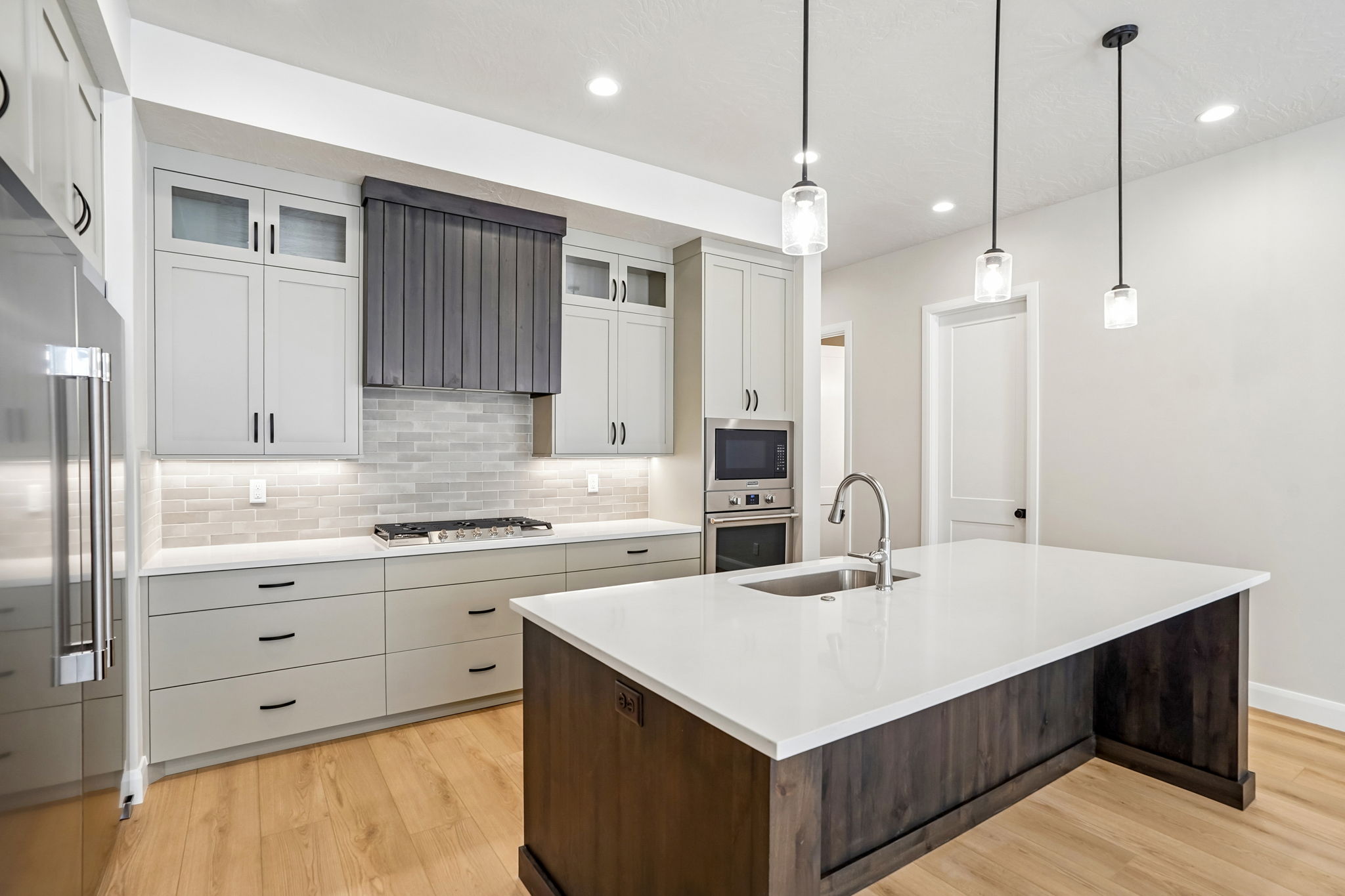 Gourmet kitchen in the Pacific II at Desert Color featuring a large dark wood island, white countertops, gray cabinetry, stainless steel appliances, and pendant lighting.