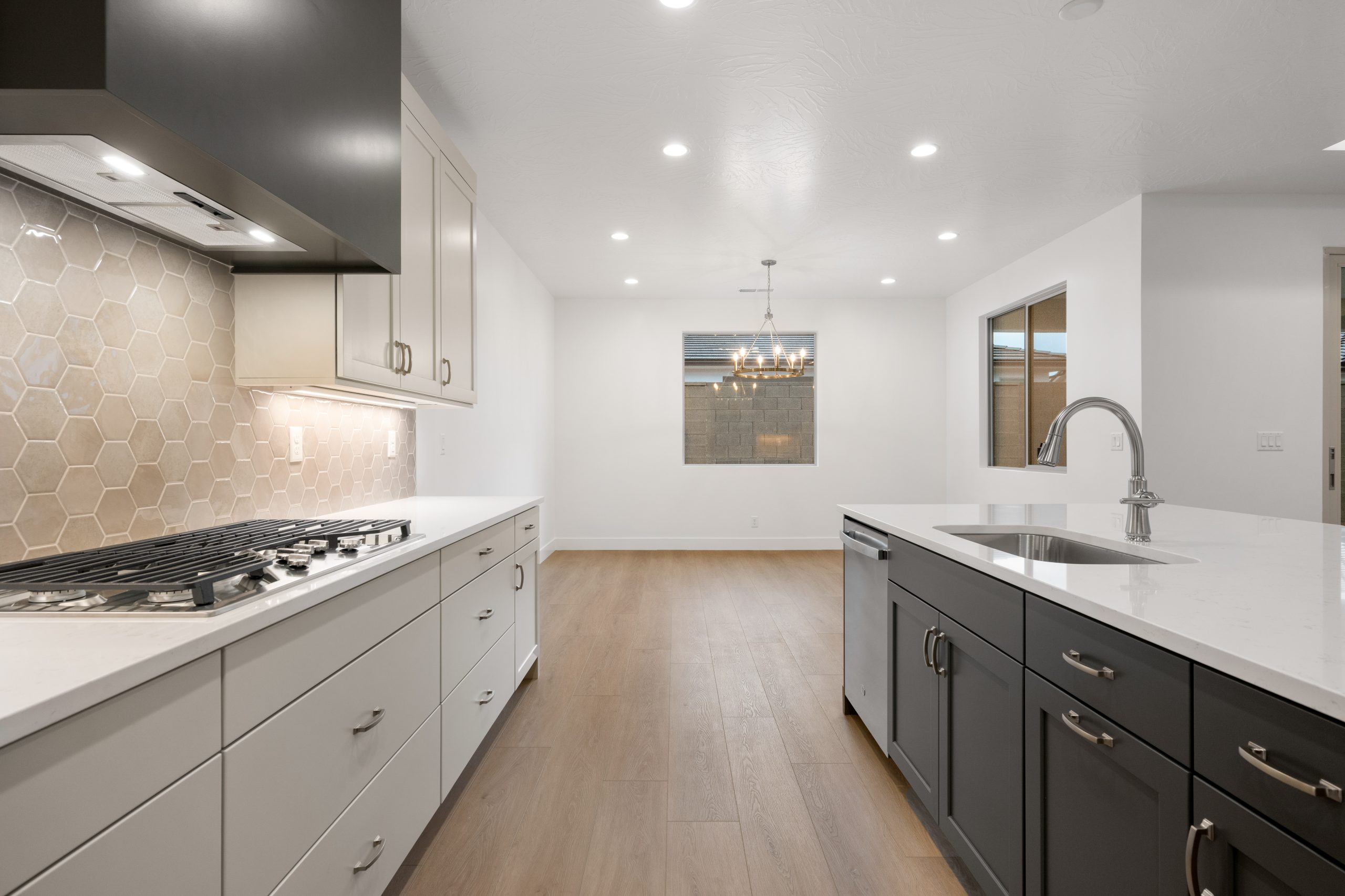 Contemporary kitchen in the Mesa floor plan at Solis by Cole West, featuring a gas cooktop, hexagon tile backsplash, dark island cabinetry, and modern finishes.