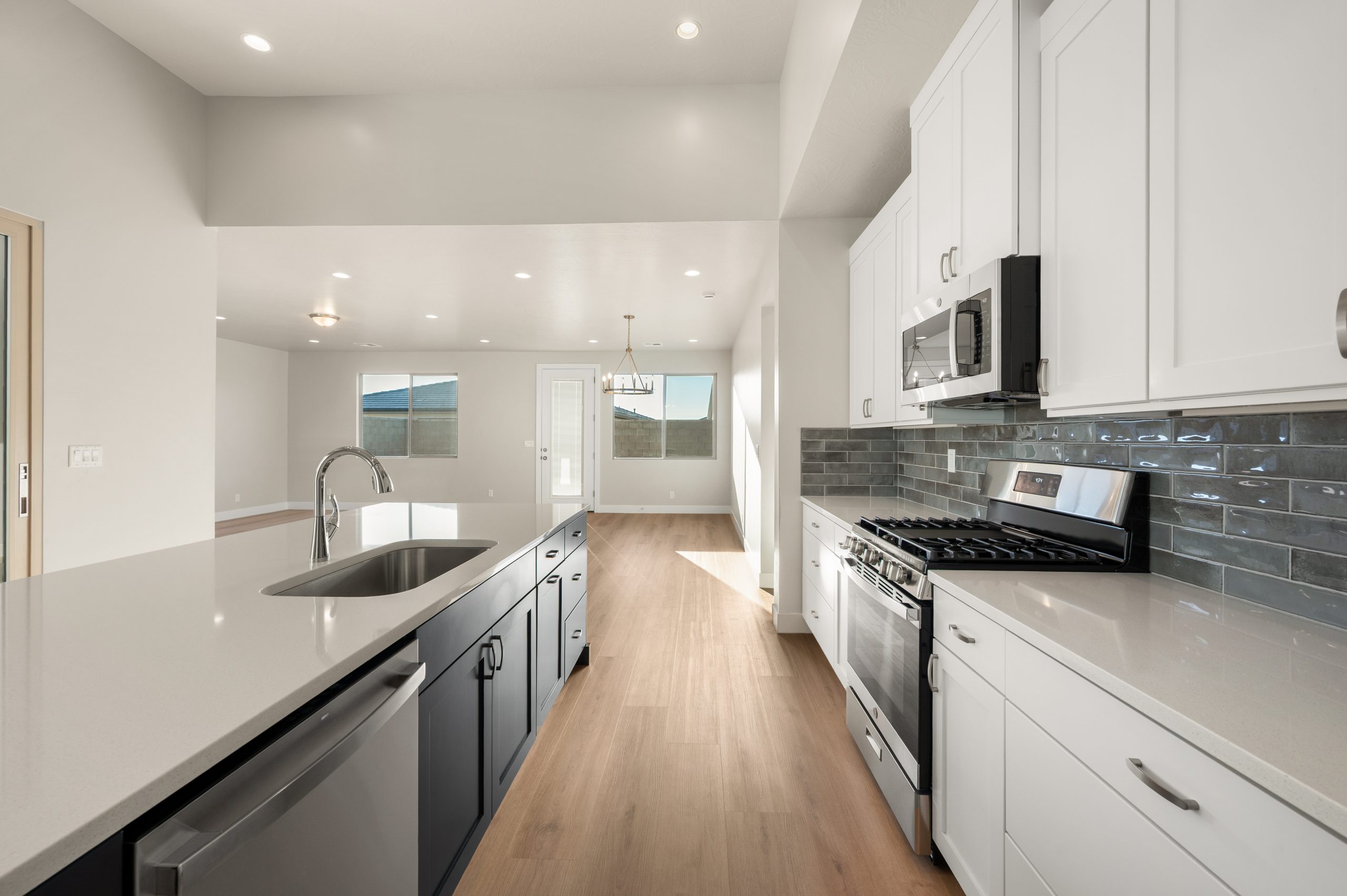 Contemporary kitchen with white shaker cabinets, stainless steel appliances, gray subway tile backsplash, and a large center island in the Mojave home at Solis.
