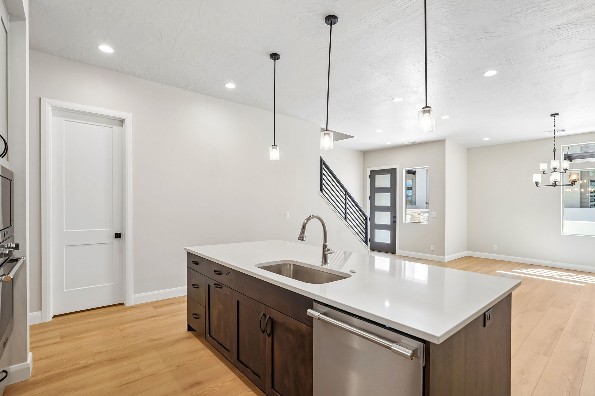 Spacious kitchen in the Pacific II at Desert Color featuring an oversized island with white countertops, dark wood cabinetry, pendant lighting, and an open-concept layout.