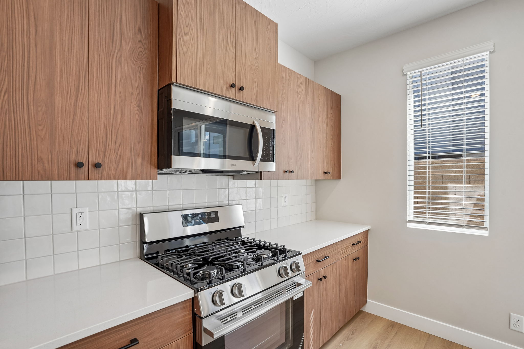Sunburst floor plan kitchen at Rise in Washington, Utah, featuring stainless steel appliances, warm wood cabinets, and white tile backsplash.