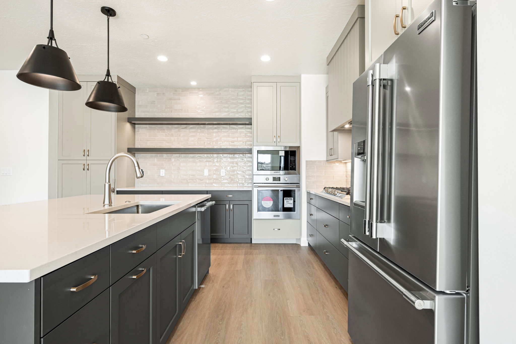 Gourmet kitchen in the Bahama floor plan featuring a large center island, stainless steel refrigerator, built-in appliances, and decorative tile backsplash.