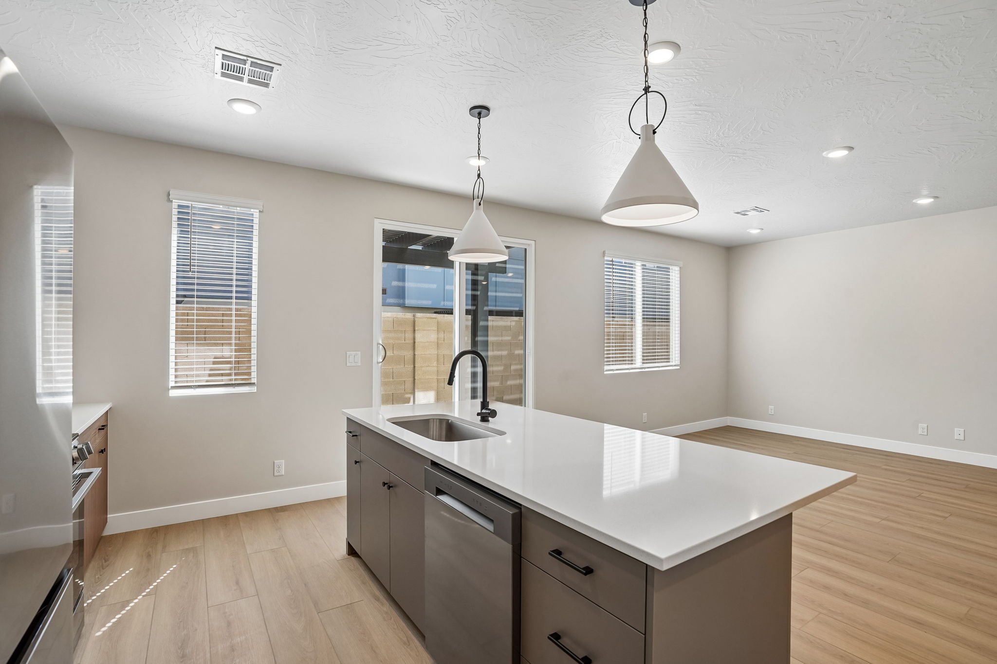 Open-concept kitchen and living area in the Sunburst floor plan at Rise, featuring a large center island, pendant lighting, and modern finishes.