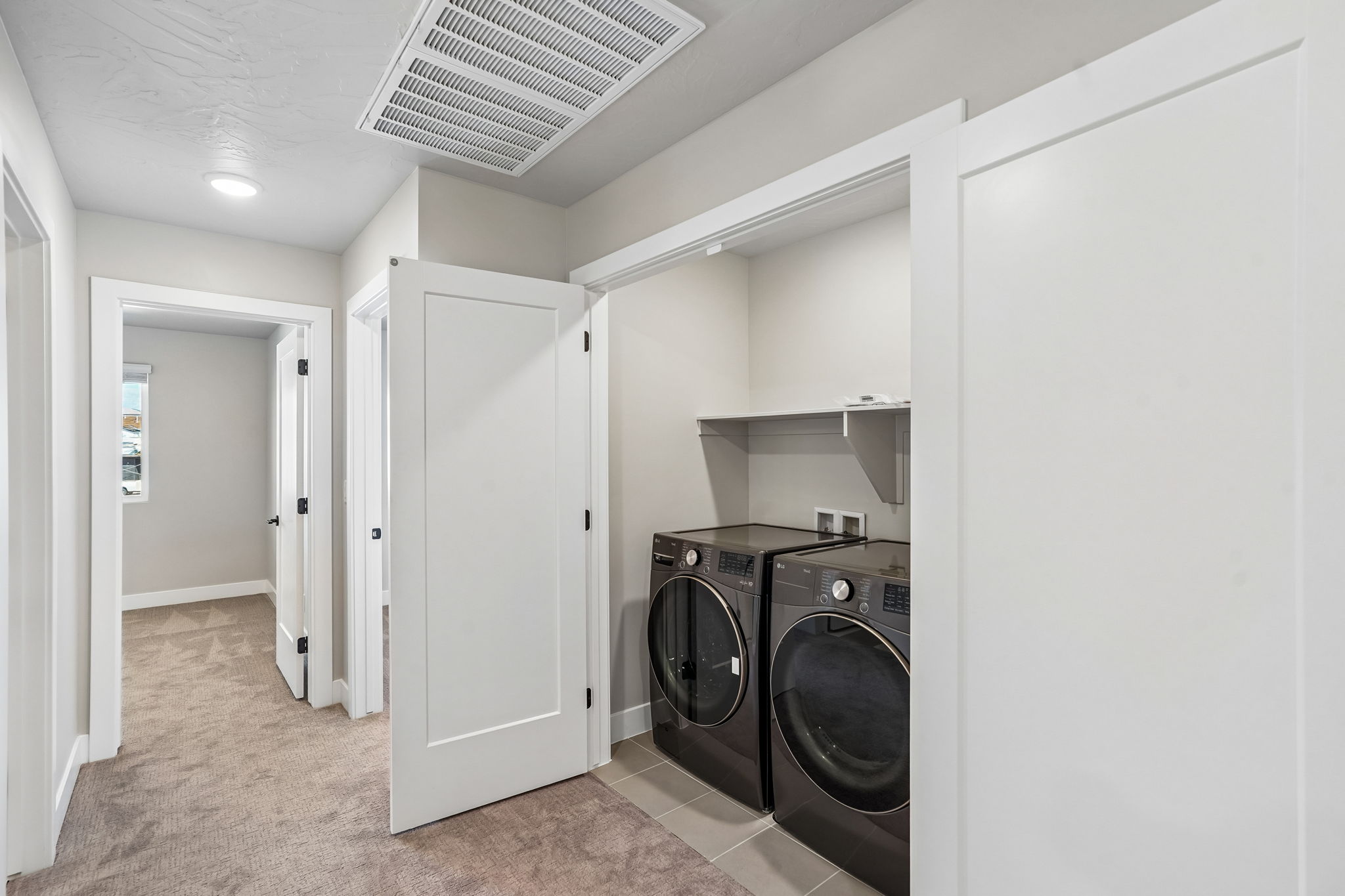 Dedicated laundry area featuring a washer, dryer, and overhead storage shelf.