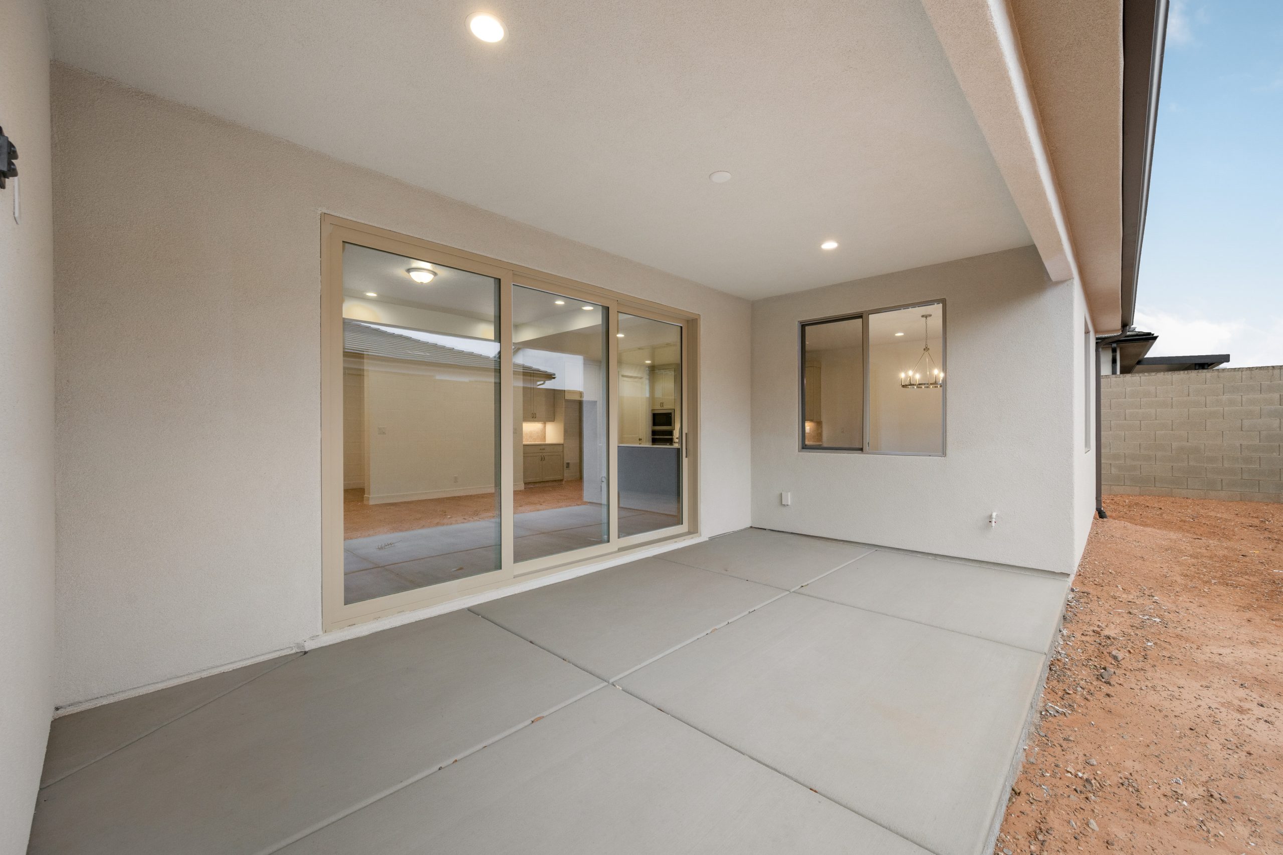 Covered backyard patio at the Mesa home in Solis, Washington, Utah, featuring a spacious concrete patio, sliding glass doors, and low-maintenance desert landscaping.