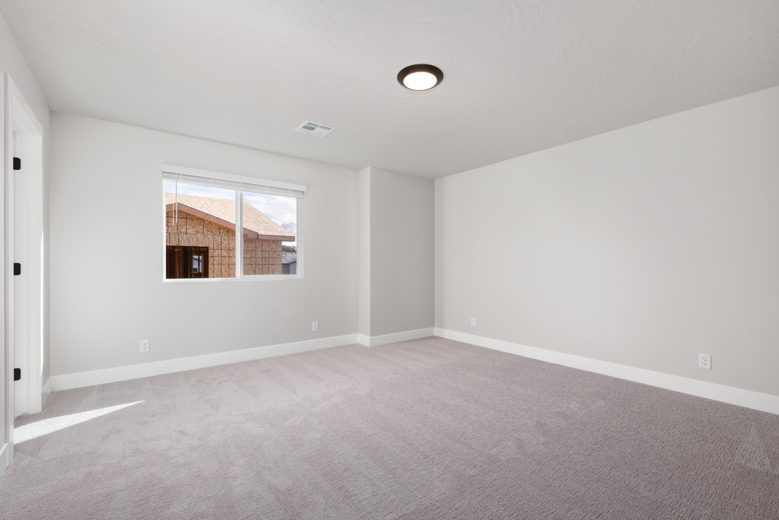 Spacious primary bedroom with plush neutral carpeting, natural light, and modern finishes in the Sunrise townhome at Rise by Cole West.