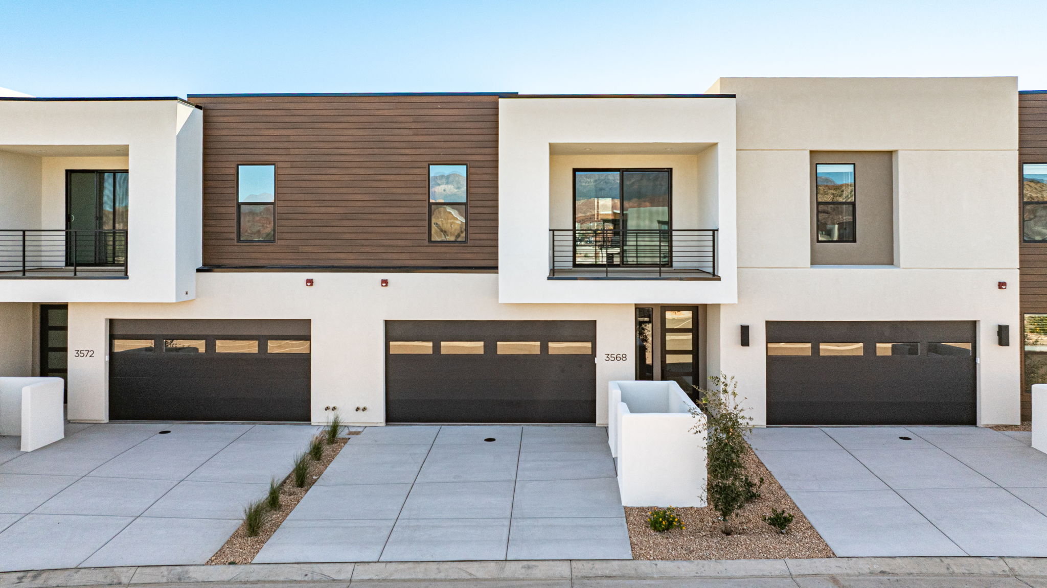 Front exterior of the Bahama townhomes at Isle by Cole West in Washington, Utah, featuring modern architecture, private balconies, and two-car garages.